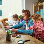 Work from home. Man works on laptop with children playing around. Family together with pet cat on table